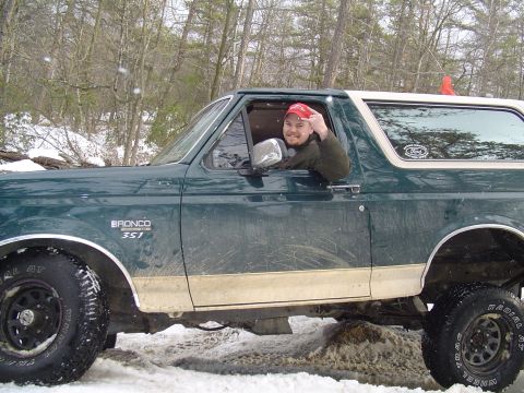 1993 Ford Bronco - A man in a red hat gives a rude gesture from the driver's seat of a green 1993 Ford Bronco in a snowy, wooded area.