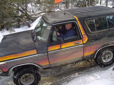 1993 Ford Bronco - Ford Bronco navigates a snowy, wooded trail with a driver behind the wheel.