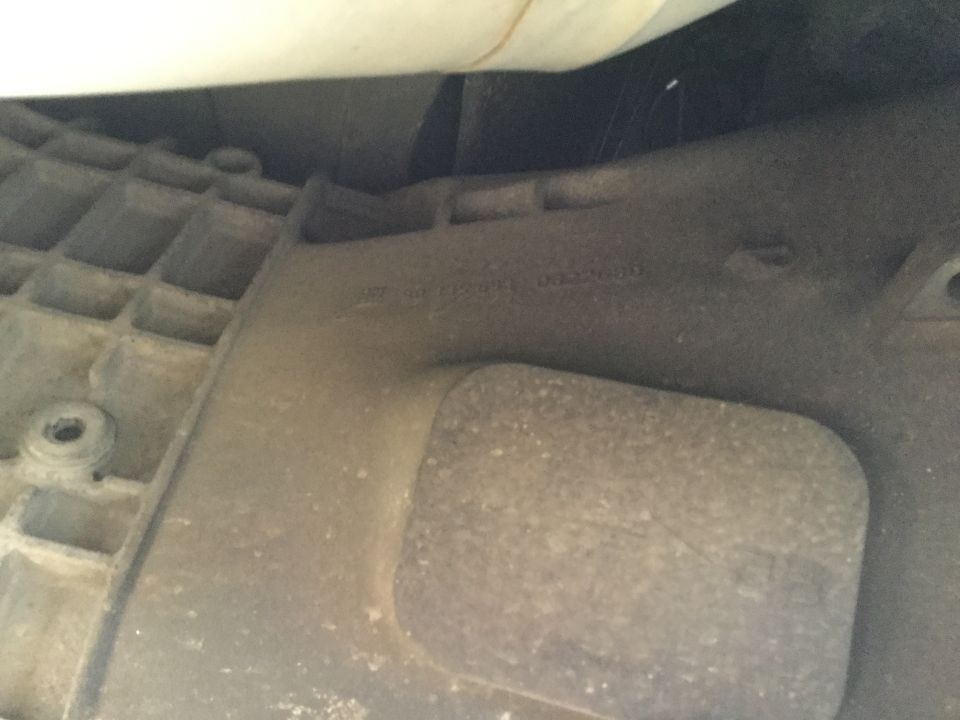 Underside of vehicle part with embossed text and grid pattern