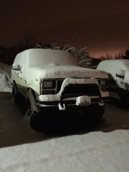 1981 Ford Bronco - A snowy night blankets a Ford Bronco and another vehicle parked outside.