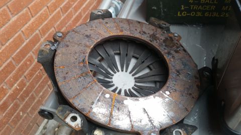 1981 Ford Bronco - A rusty clutch disc and pressure plate assembly is shown, with some text visible on a box in the background.