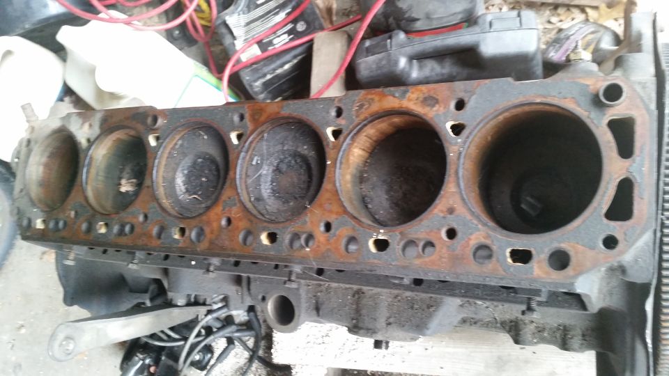 Rusty engine block with six cylinders visible, some with carbon buildup