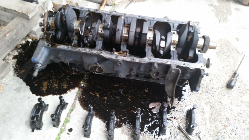 Engine block with crankshaft and connecting rods laid out, surrounded by oil