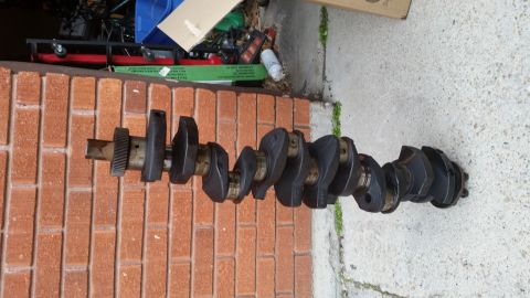 1981 Ford Bronco - A crankshaft with a gear attached is shown against a brick wall.