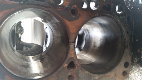 1981 Ford Bronco - Close-up view of engine block cylinders, showing internal wear and oil. A tire is visible in the reflection of the left cylinder.