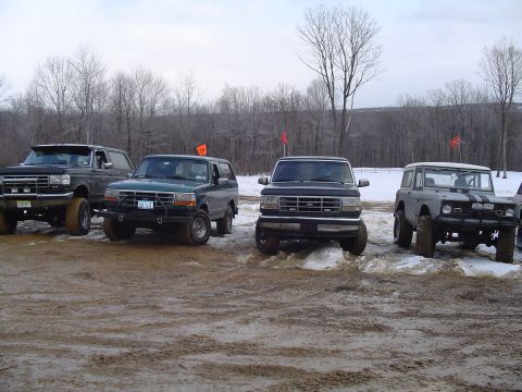 1993 Ford Bronco - Several Ford Broncos are lined up in a wintery, outdoor setting with muddy terrain.