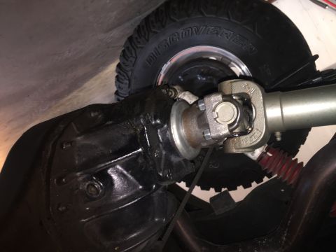 1982 Ford Bronco - Close-up view of drivetrain components and a tire, with visible text on the tire sidewall.