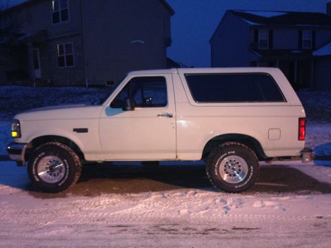 1993 Ford Bronco - A white 1993 Ford Bronco is parked on a snow-covered street at dusk.