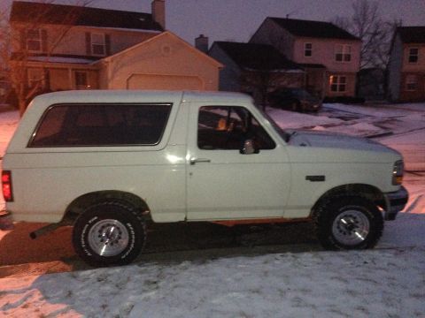 1993 Ford Bronco - Side view of a white Ford Bronco in a snowy residential area during twilight.