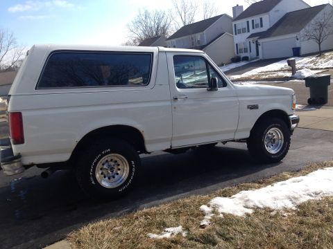 1993 Ford Bronco - This white Ford Bronco is shown from the side, parked in a suburban neighborhood during winter.