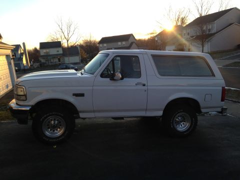 1993 Ford Bronco - This white Ford Bronco is viewed from the side during a sunset, parked in a residential area.