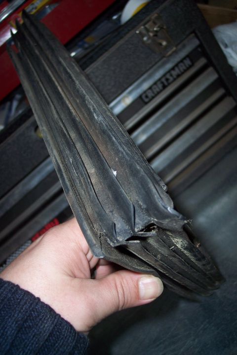 1990 Ford Bronco - A hand holds a damaged rubber seal, likely for a vehicle window or door.