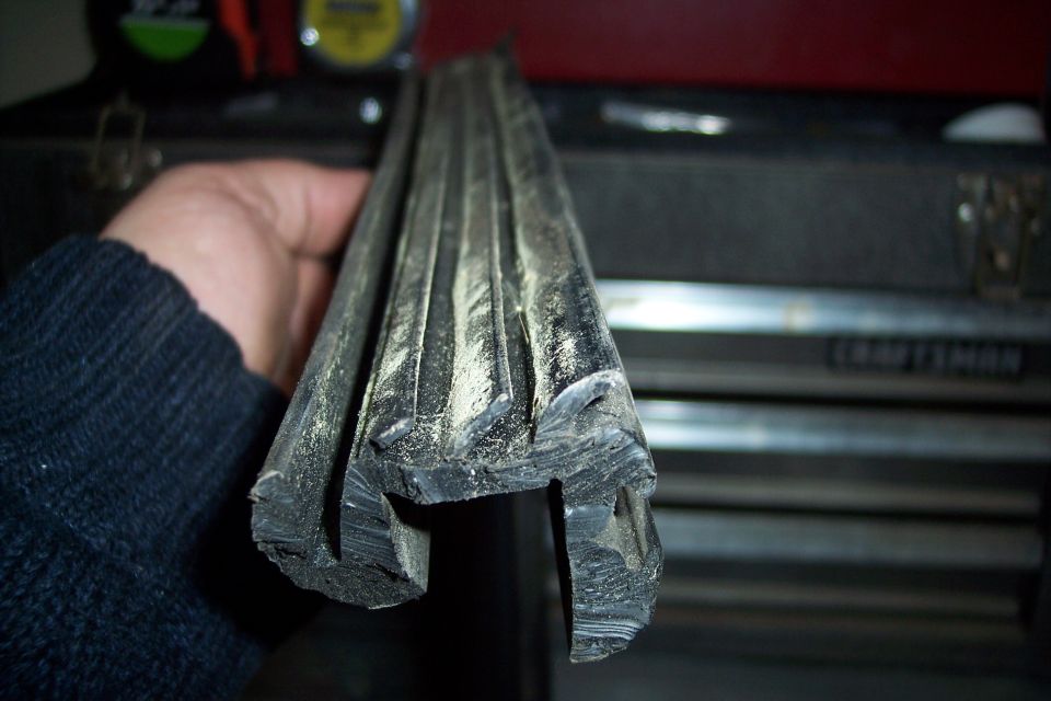 Rubber slider gasket with dust, held by a hand wearing a dark sweater. A toolbox is in the background