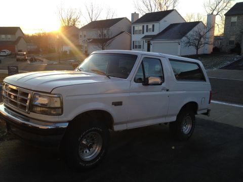 1993 Ford Bronco - A white 1993 Ford Bronco is parked in a suburban driveway during the golden hour.