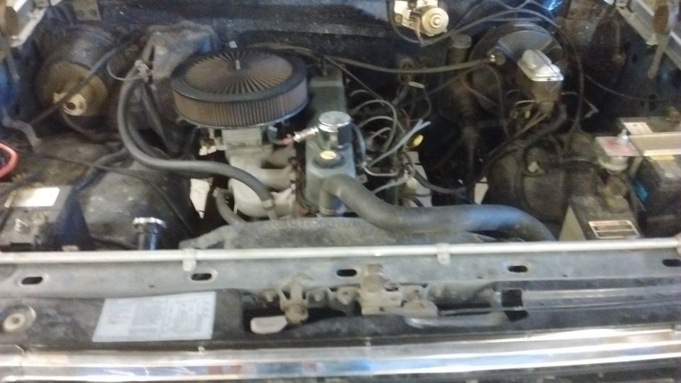 Engine bay with V8 engine, air filter, radiator hoses, and battery