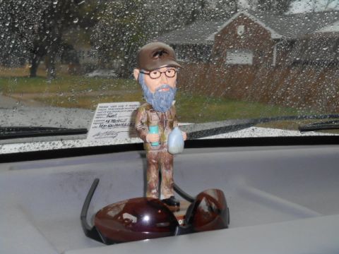 1972 Ford Bronco - A bobblehead figure is placed on the dashboard of a vehicle on a rainy day.