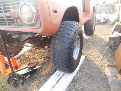 1972 Ford Bronco - The front end of a classic Ford Bronco is shown, supported by jack stands and resting on wooden planks.