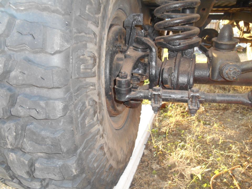 Close-up of a large off-road tire and front suspension components. Visible text: 'SUPER MOTORS'