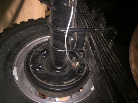 1982 Ford Bronco - Close-up view of the rear axle and leaf spring assembly, including the brake drum and tire.