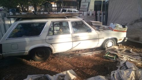 1980 Ford Fairmont - A white 1980 Ford Fairmont station wagon sits in a yard, appearing weathered and unused.
