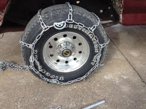 1996 Ford Bronco - Tire chains are installed on a vehicle's tire for traction in snowy conditions.