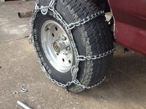 1996 Ford Bronco - A close-up view of a vehicle's tire fitted with snow chains, ready for winter conditions.