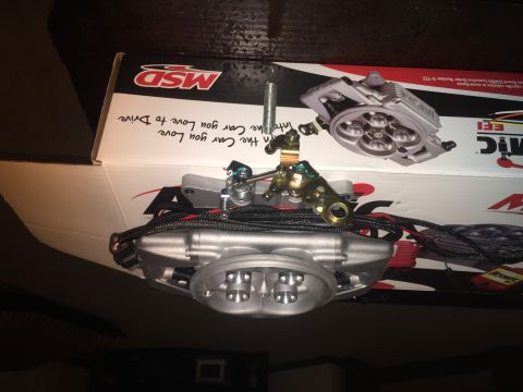 1982 Ford Bronco - A close-up, overhead view of a silver fuel injection throttle body assembly resting on top of a black and white MSD box. Text on the box re…