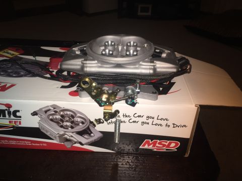 1982 Ford Bronco - A new MSD Atomic EFI throttle body and associated wiring are displayed on top of its original packaging. The box has text that reads "Into…