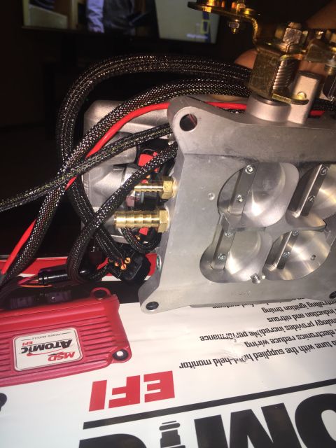 1982 Ford Bronco - A close-up view of a performance engine part, likely a throttle body, with associated wiring and a red MSD Atomic EFI power module. The eng…