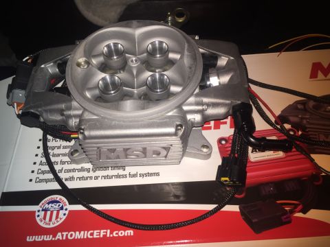 1982 Ford Bronco - A silver MSD Atomic EFI throttle body is shown in a close-up shot, resting on a box with "Proudly Made in the U.S.A." text and a website ad…