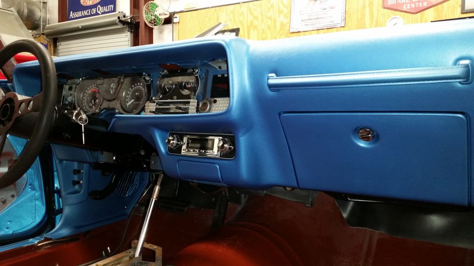 Blue dashboard interior of a classic car with a radio and key in the ignition.