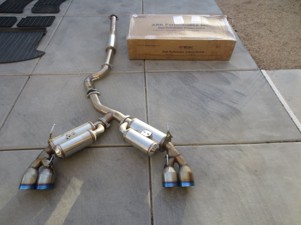 ARK Performance exhaust system with blue tips and a box on a tiled surface.