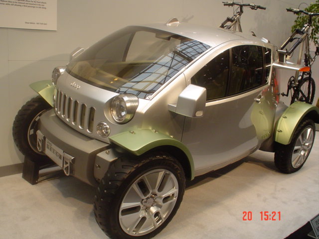 Silver and green Jeep concept micro-vehicle on display with bicycles mounted at rear