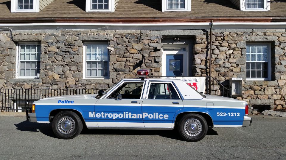 Vintage Metropolitan Police sedan parked in front of a stone building