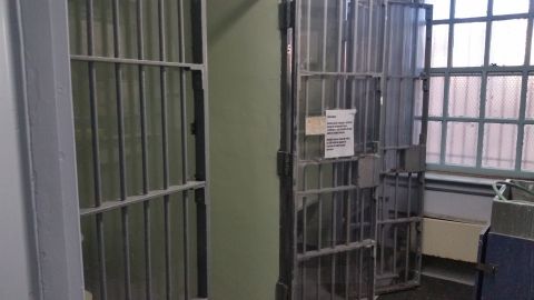 1991 Ford LTD Crown Victoria - Photograph of vintage steel-barred jail cells with a posted paper notice on the bars.