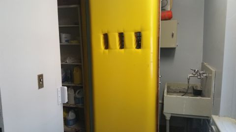 1991 Ford LTD Crown Victoria - Photograph of a yellow flammable-storage cabinet next to a utility sink and shelving.