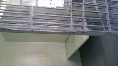 1991 Ford LTD Crown Victoria - Photograph of an empty jail cell with a wall bench viewed through steel bars.