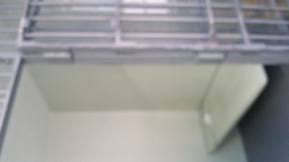 Interior of a jail cell with bunk and barred door, slightly out of focus