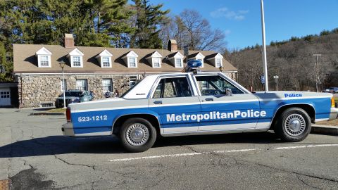 1991 Ford LTD Crown Victoria - Photo of a Metropolitan Police Ford Crown Victoria cruiser, side profile outside a stone police station.