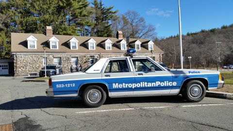 1991 Ford LTD Crown Victoria - Photo of a Metropolitan Police Ford Crown Victoria cruiser parked at a stone police station.