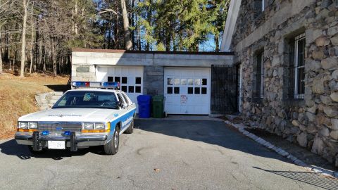 1991 Ford LTD Crown Victoria - Photo of a vintage Ford Metropolitan Police patrol car on a driveway beside a stone garage, not a technical document.