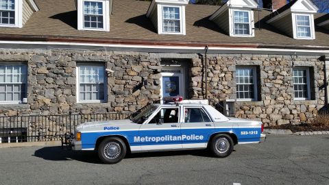 1991 Ford LTD Crown Victoria - Photo of a vintage Ford Metropolitan Police patrol car parked in front of a stone building, not a technical document.