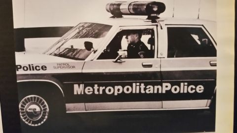 1991 Ford LTD Crown Victoria - Photo of a black-and-white print showing an officer in a Metropolitan Police patrol car, not a technical document.