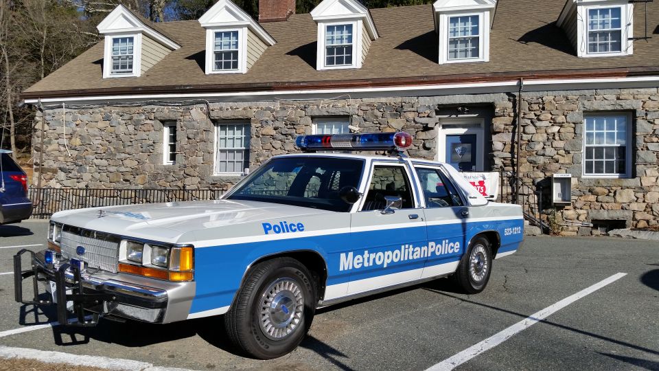Metropolitan Police Ford sedan parked in front of stone station