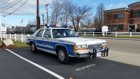 1991 Ford LTD Crown Victoria - Photo of a vintage Ford Metropolitan Police patrol car parked in a reserved roadside spot, not a technical document.