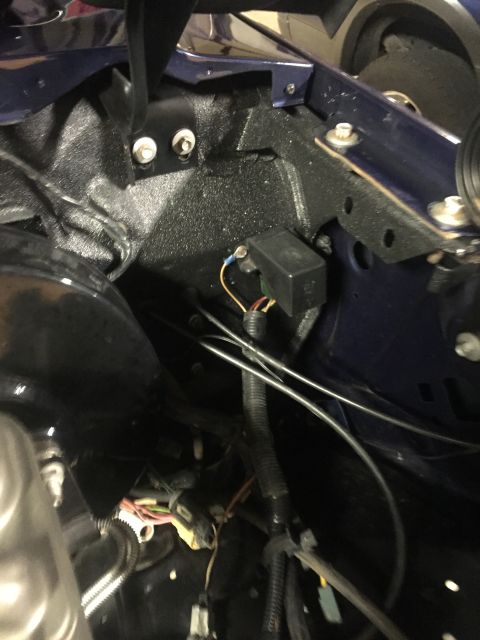 1982 Ford Bronco - A close-up view of the engine bay of a dark blue vehicle, showing wiring harnesses, a black electrical box, and mounting brackets.