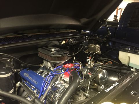 1982 Ford Bronco - Close-up view of a modified V8 engine bay, featuring a blue Ford Racing valve cover, chrome air cleaner, and blue spark plug wires. The eng…