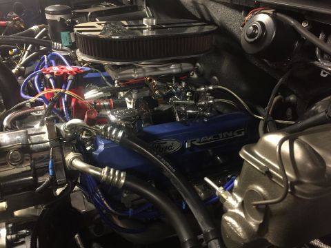 1982 Ford Bronco - A close-up view of a Ford Racing engine bay, featuring a blue valve cover with silver lettering, a chrome air cleaner, and various hoses an…