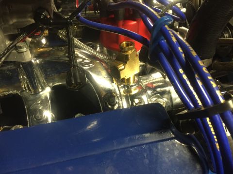 1982 Ford Bronco - A close-up view of the engine bay of a 1982 Ford Bronco shows a chrome-plated intake manifold with a brass T-fitting and blue spark plug wi…