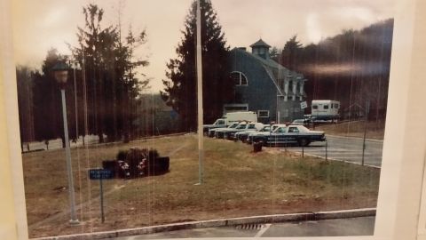 1991 Ford LTD Crown Victoria - Several police cruisers, likely Ford Crown Victorias, are parked outside a building. A trailer is also visible.